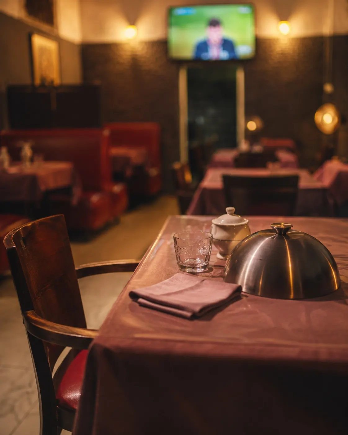 La salle de L'Expatrié : tables nappées de mauve, banquettes rouges et lumières chaudes.